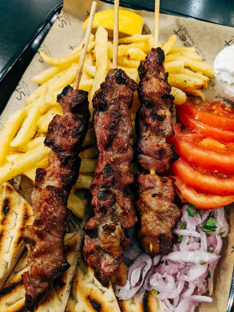 Image of Souvlaki made with grilled meat, threaded onto skewers. Flavored with olive oil, lemon juice, oregano, and garlic.
