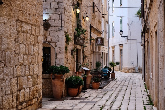 stone street in alley in croatia with potted plants and a restaurant