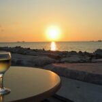 glass of greek white wines on a table with sunset in background