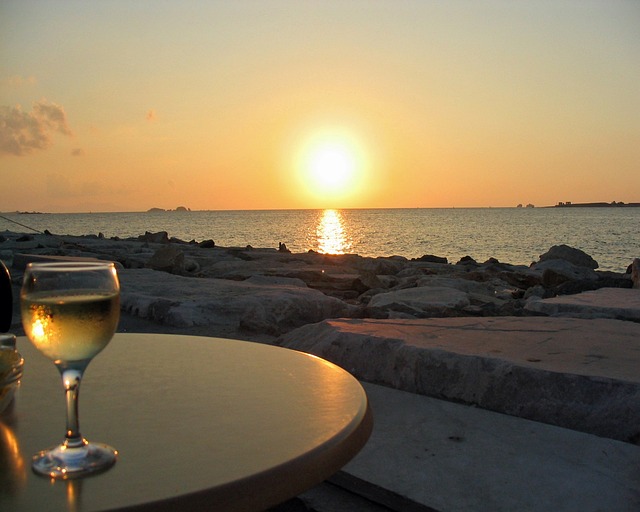 glass of greek white wines on a table with sunset in background
