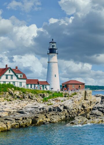 A picturesque lighthouse stands on the rugged shoreline, enhancing the beauty of Portland's stunning view.