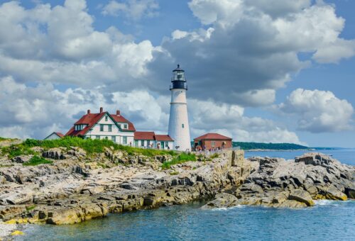 A picturesque lighthouse stands on the rugged shoreline, enhancing the beauty of Portland's stunning view.